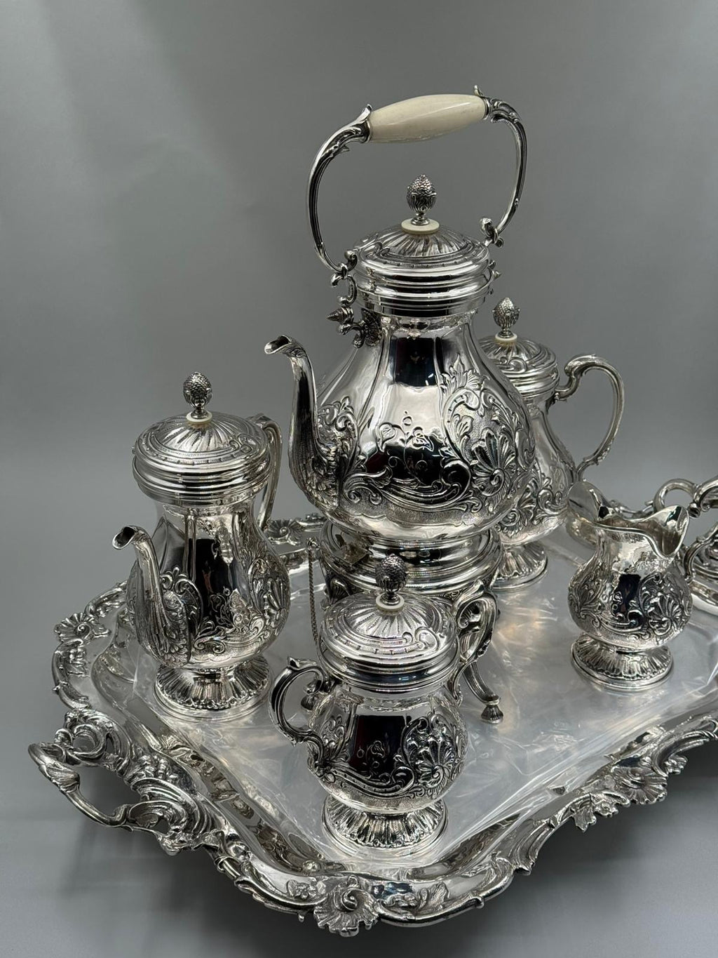 Silver tea set with intricate designs on a gray background