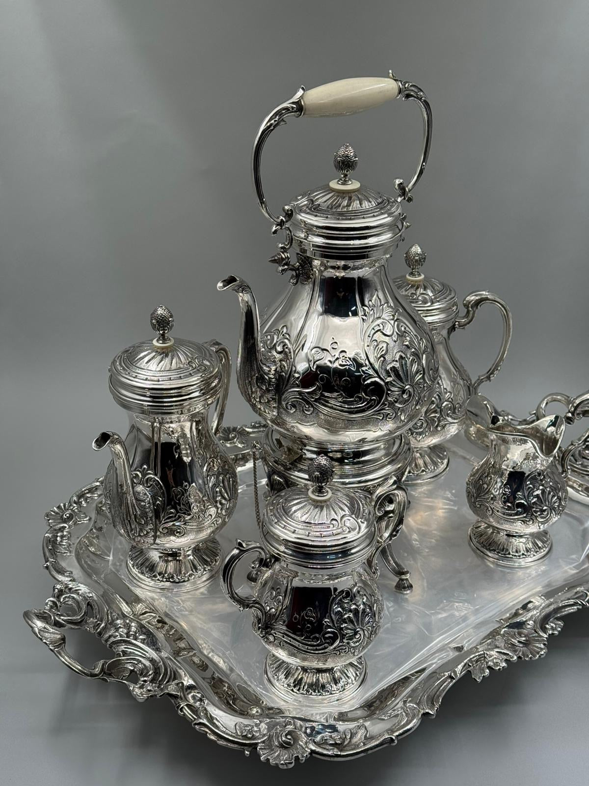 Silver tea set with intricate designs on a gray background